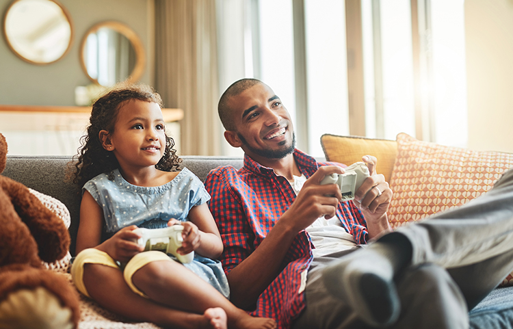 Father and daughter sitting on the couch playing a video game